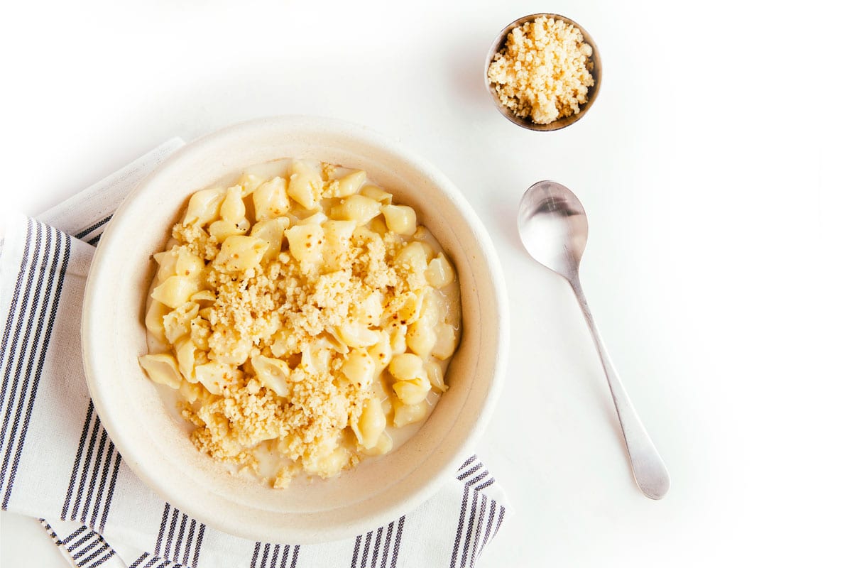Aerial view of a bowl of mac and cheese with pie crust on the top. There is a spoon on the side of the bowl.