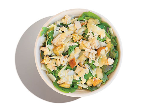 Caesar-style salad with grilled chicken, croutons, shaved Parmesan, and dressing on leafy greens.