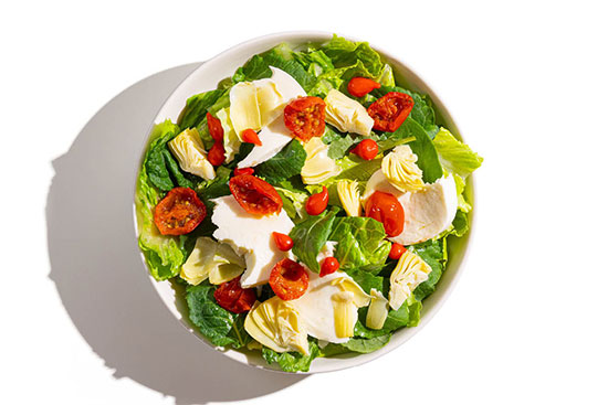 Salad with romaine lettuce, mozzarella, cherry tomatoes, and artichoke hearts.