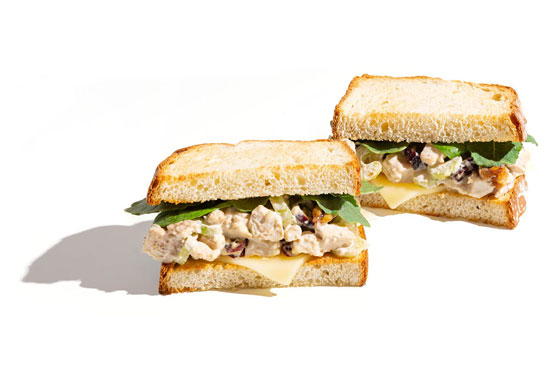 Chicken salad sandwiches with cheese and leafy greens on thick toasted bread.