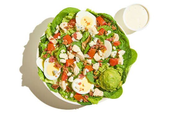 Cobb salad with hard-boiled eggs, grilled chicken, avocado, bacon, blue cheese, tomatoes, and ranch dressing.