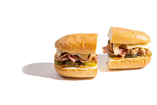 Deli sandwiches with ham, pickles, cheese, and mustard on crusty rolls.