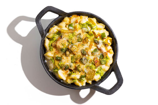 Mac and cheese skillet loaded with broccoli, green peppers, and melted cheese.