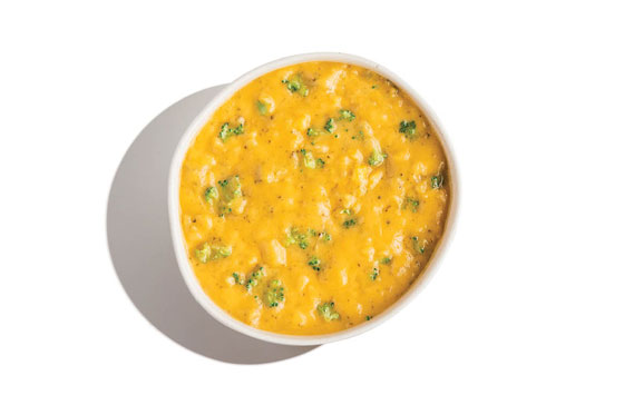 Cheddar broccoli soup with visible broccoli florets in a thick yellow cheese base.
