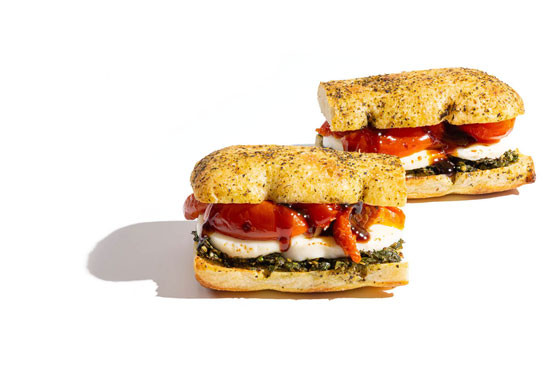Caprese-style sandwiches with mozzarella, pesto, and roasted tomatoes on herb focaccia rolls.