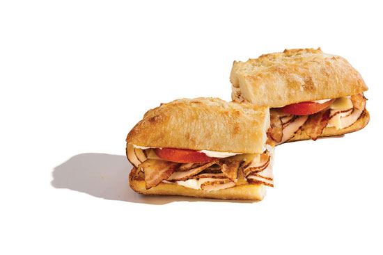 Sliced turkey sandwiches with tomato on crusty rolls.