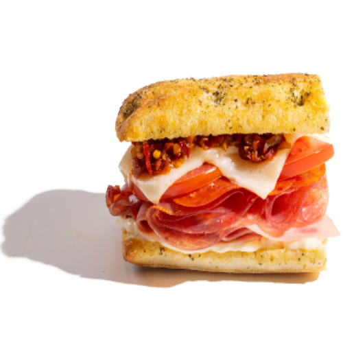 Italian-style sandwich with layers of cured meats, sliced tomatoes, melted cheese, and a spicy relish on a toasted herb focaccia roll.