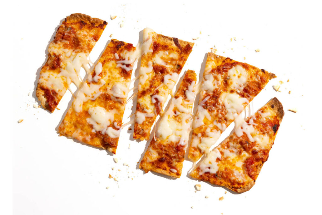 Sliced cheese flatbread pizza with golden melted mozzarella and tomato sauce.