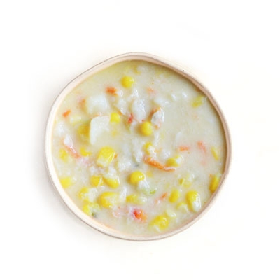 Corn chowder with visible corn kernels, diced potatoes, and carrots in a creamy base.
