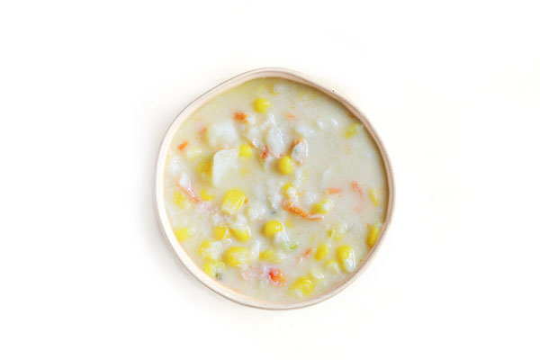 Corn chowder with visible corn kernels, diced potatoes, and carrots in a creamy base.