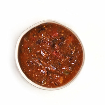 Thick tomato-based soup or salsa with black beans, peppers, and herbs.