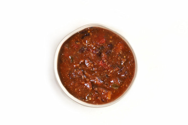 Thick tomato-based soup or salsa with black beans, peppers, and herbs.