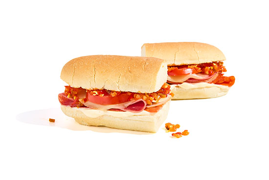 Sub sandwiches with deli meats, tomatoes, cheese, and spicy relish on hoagie rolls.