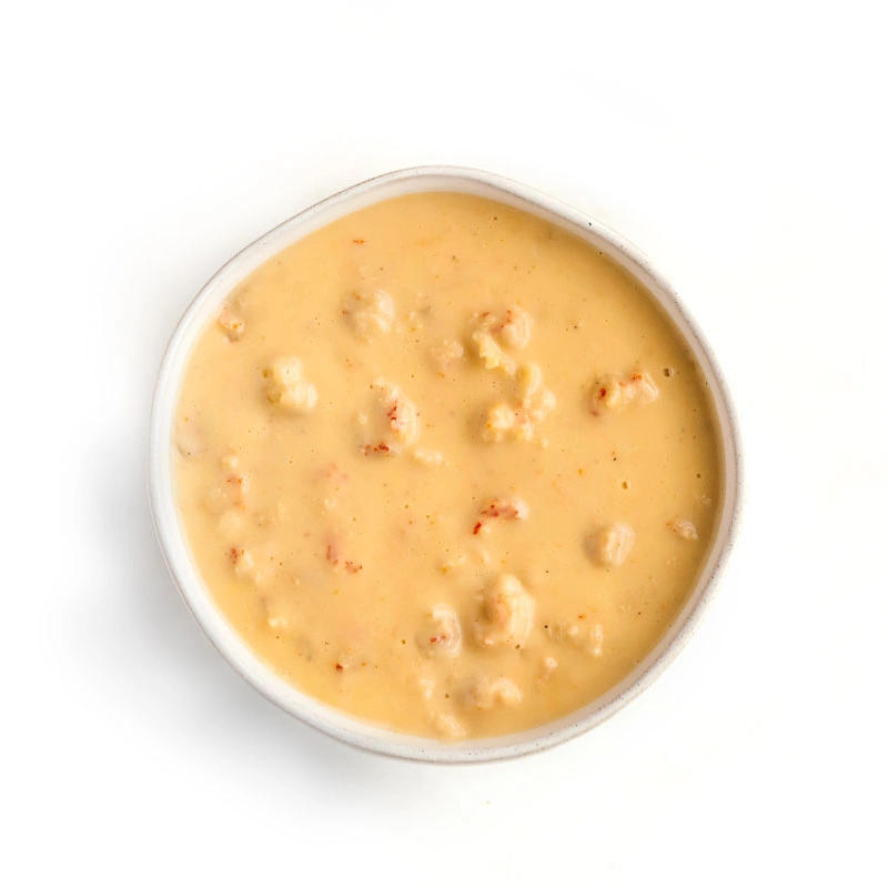 Creamy bisque with small chunks of lobster or seafood in a light orange broth.