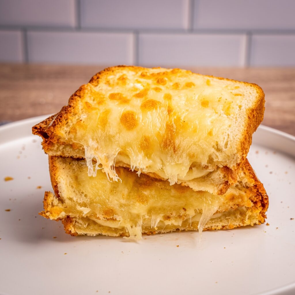 A gooey grilled cheese sandwich with melted cheese stretching between two golden slices of toasted bread.