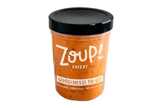 A plastic container of soup from Zoup! Eatery with a black lid, labeled “GOOD(NESS) TO GO,” and marked as freezable, BPA-free, and microwavable.