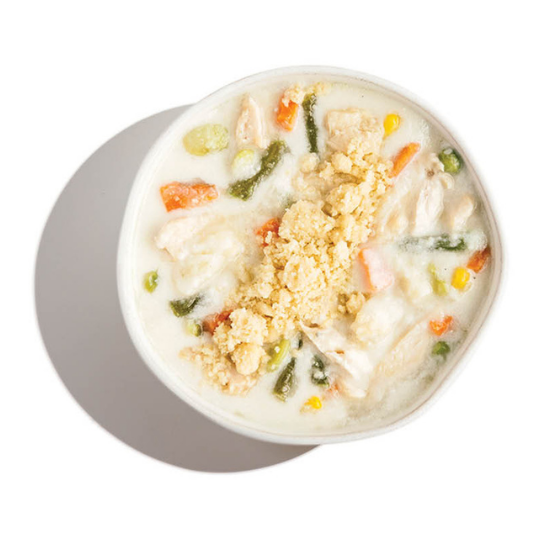 Overhead view of a creamy white chicken and vegetable soup topped with a crumbly garnish in a white bowl.