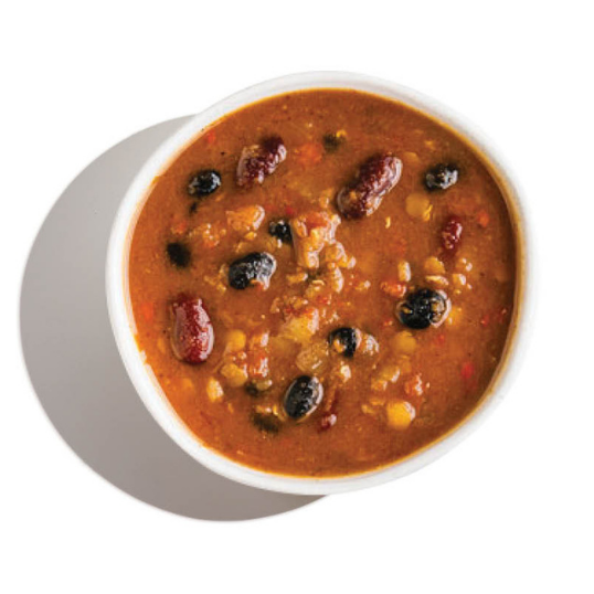 Overhead view of a red bean and vegetable chili in a white bowl, with kidney beans and black beans visible.